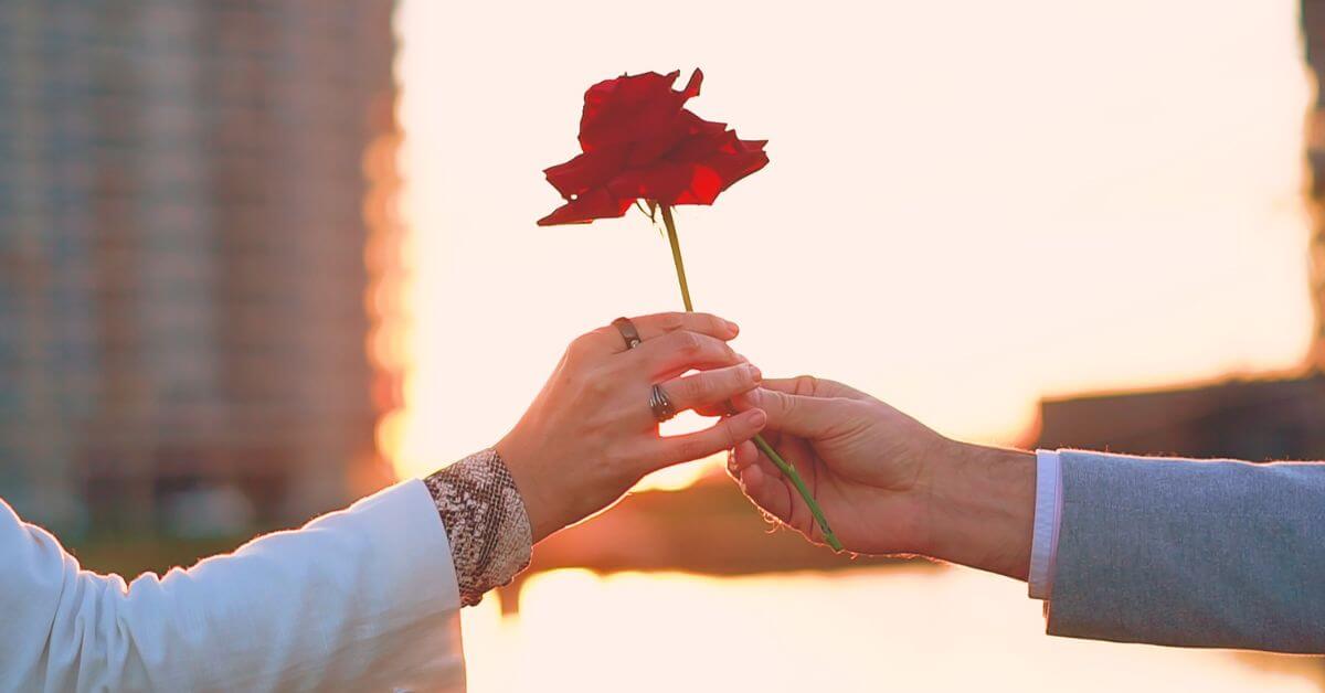 Imagem de uma mão masculina entregando uma rosa para uma mão feminina, ao que parece serem as mãos de um casal, em uma cerimônia matrimonial. Imagem destacada do site louvare.com, referente ao post: Devocional: Amor e respeito no relacionamento: Um relacionamento conjugal abençoado com Efésios 5:33