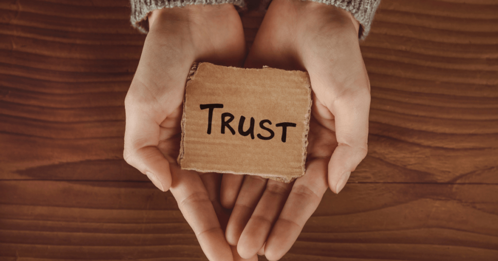 Imagem de uma par de mãos segurando algumas letras, que formam a palavra em inglês "Trust", que em português significa "Confiar". Imagem destacada do site louvare.com, referente ao post: Estratégias bíblicas para vencer o medo e confiar em Deus em todas as circunstâncias