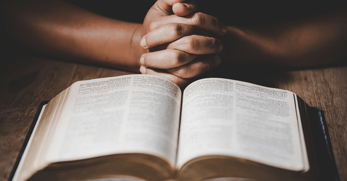 Imagem de duas mãos juntas, em cima de uma Bíblia aberta. Imagem destacada do site louvare.com, referente ao post: Reflexão: Versículo Números 6:24-26 – Bênção divina